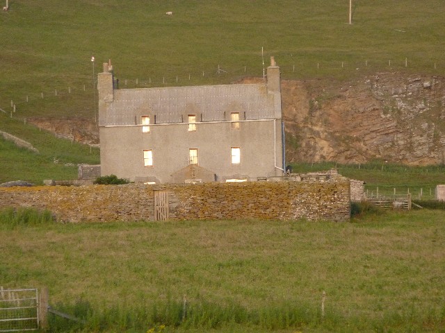 Evening sun reflected in windows of the manor house built when Jarlshof no longer used