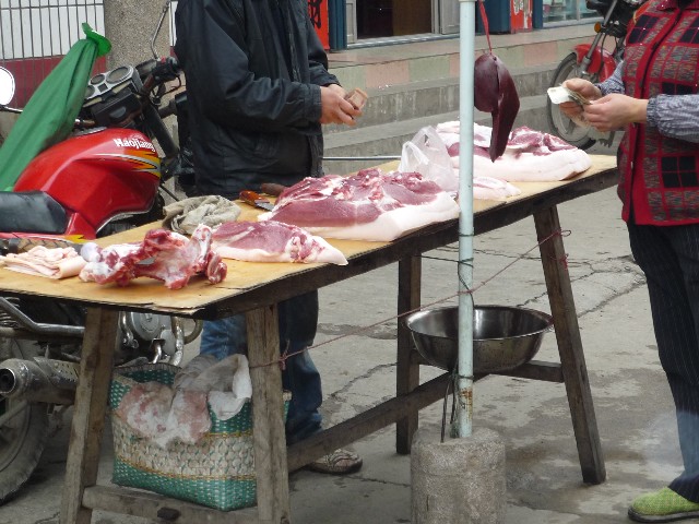 Pig owner selling his pork in the village