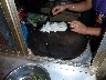 Lady chopping noodles from a lump of rice pate